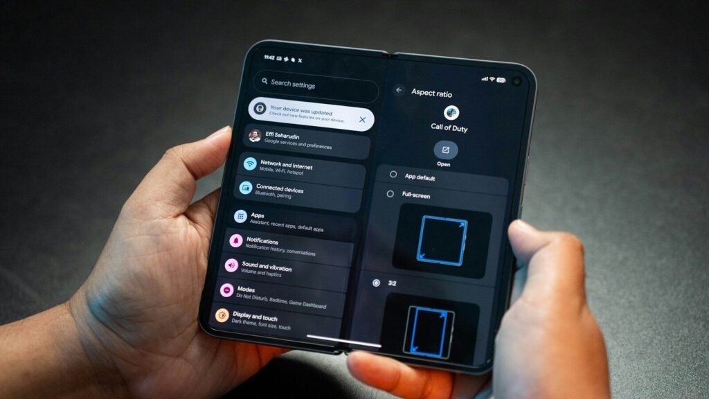 Hands holding a foldable smartphone showing its settings menu, illustrating foldable phones in 2026